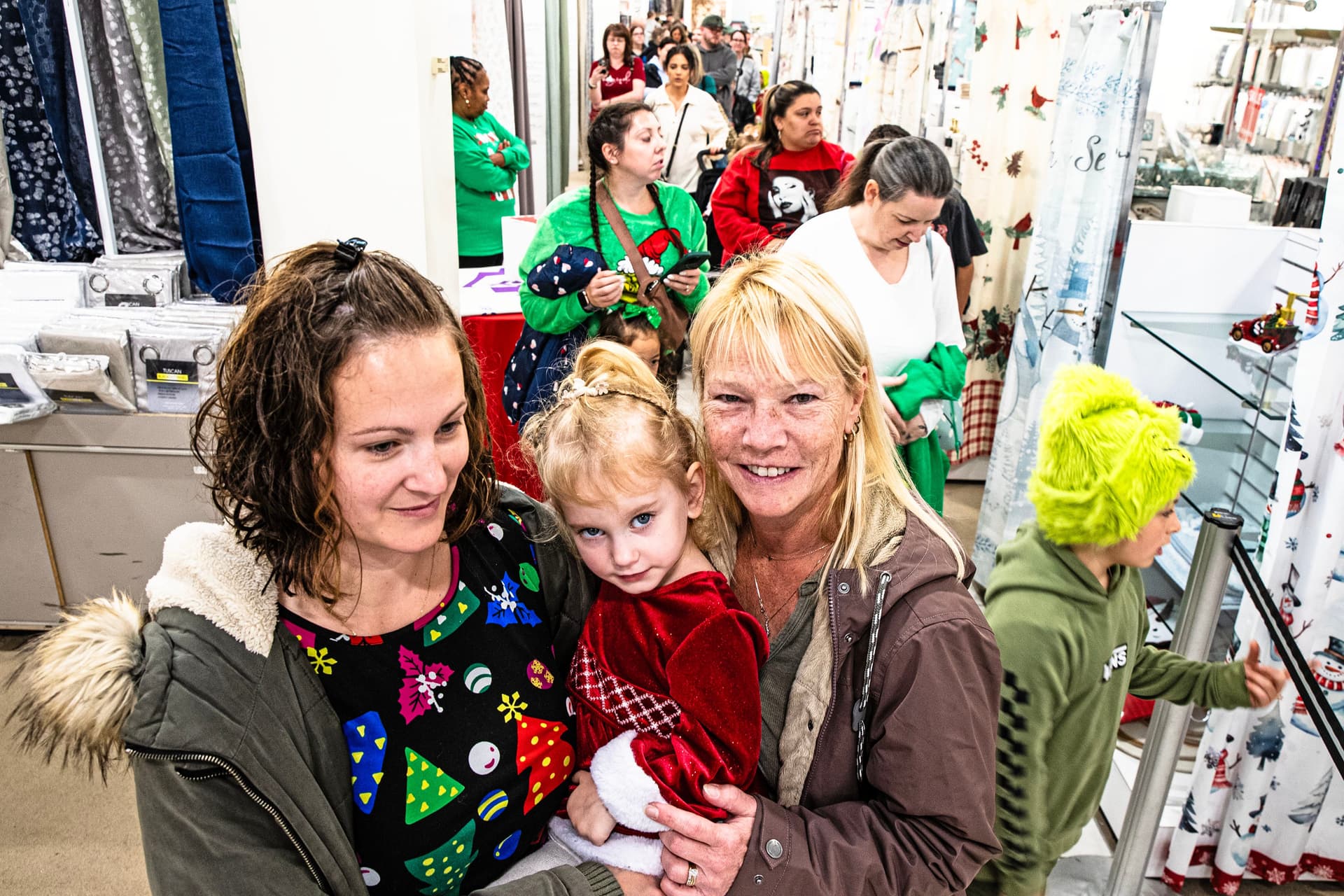 A family waits in the long queue to take photos with the Grinch inside Boscov’s department store during a Grinch event held in Christiana on Nov. 22, 2025.